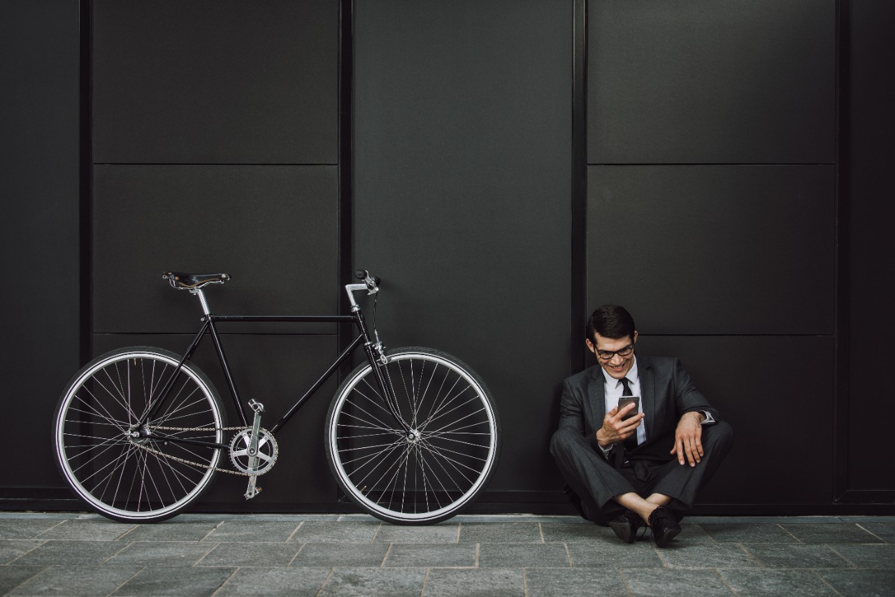 Handsome young business man with his modern bicycle.