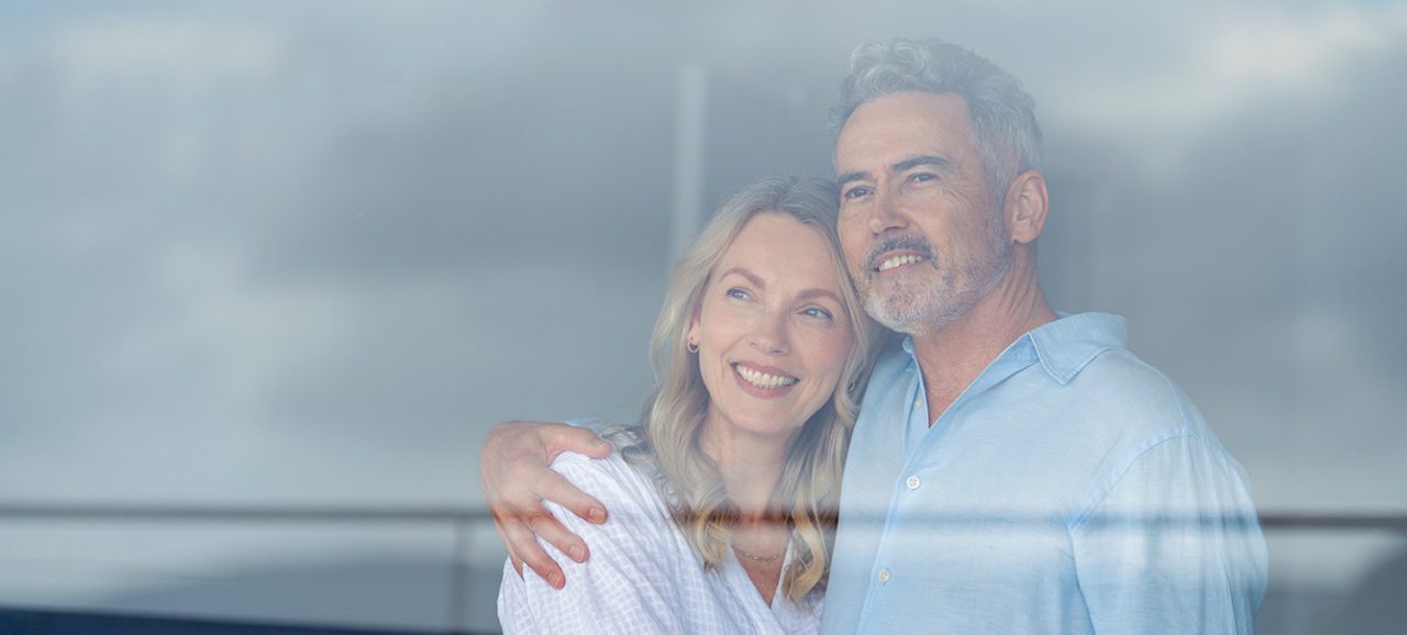 Un couple souriant regardant à travers la vitre