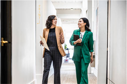 Deux femmes habillées en costumes, discutant en marchant dans des bureaux