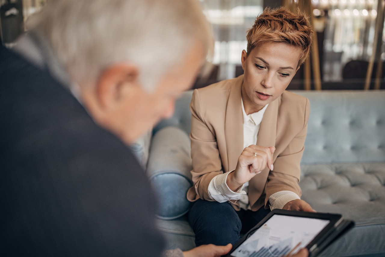 Relationship Manager A woman showing a graph on a tablet to a men