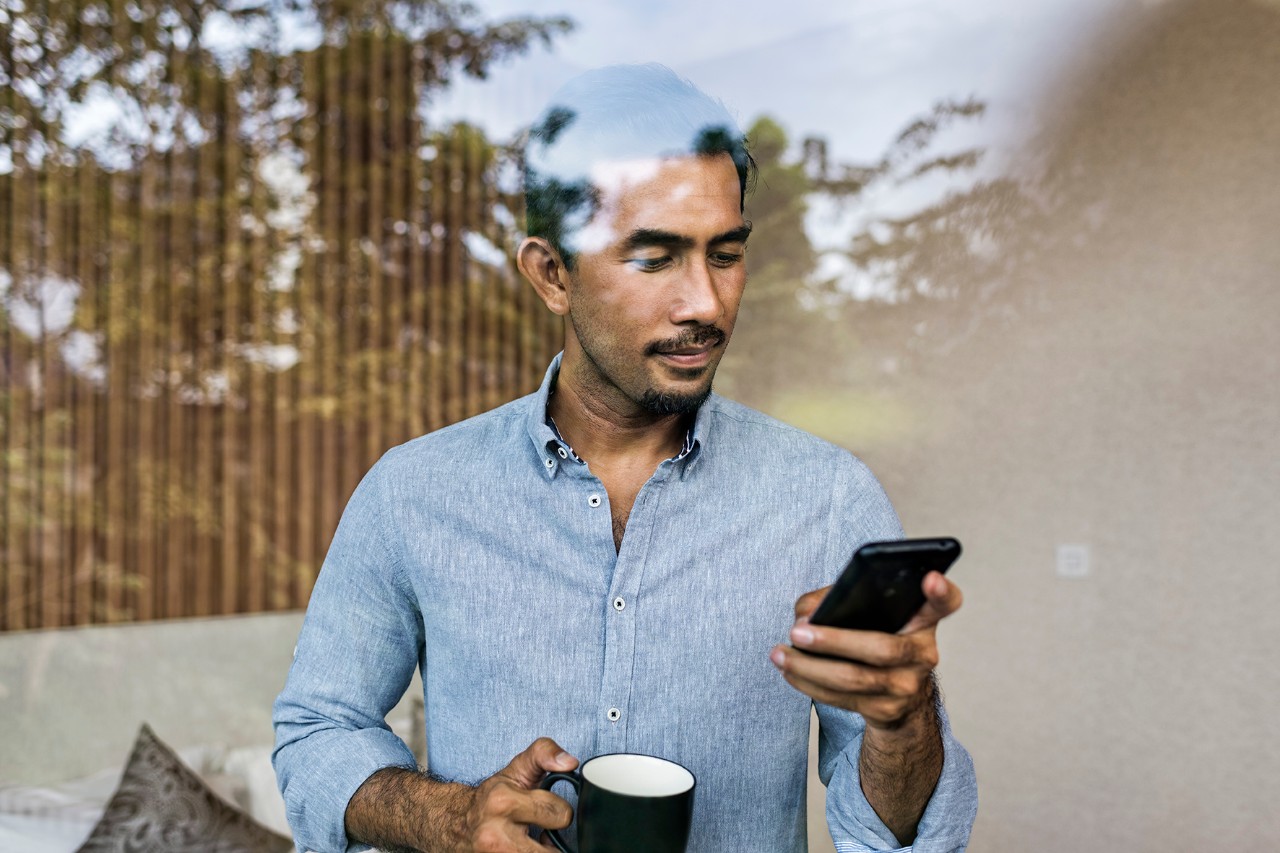 Portfolio Advisor A man looking at his phone while drinking his coffee