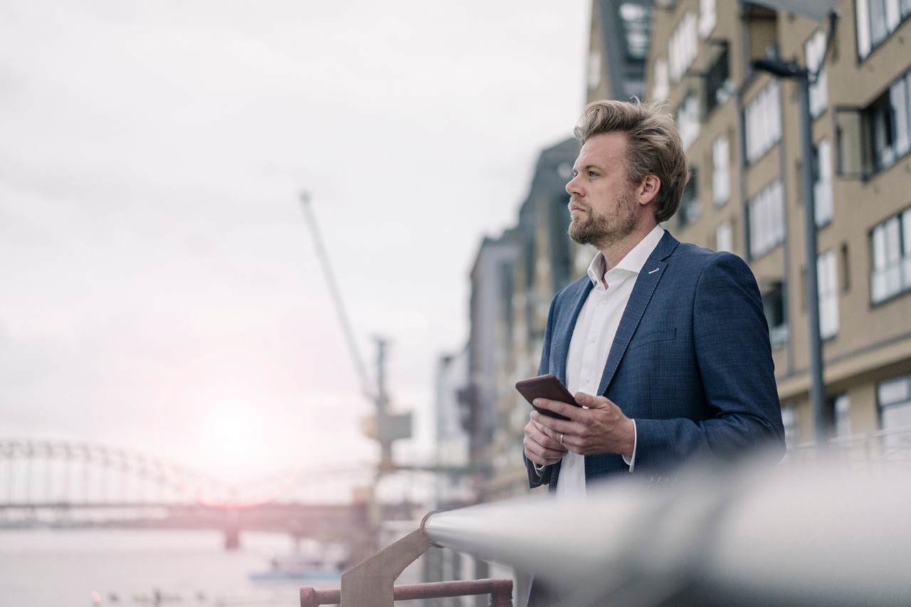 Credit Officer  A man holding a phone on the banks of a canal